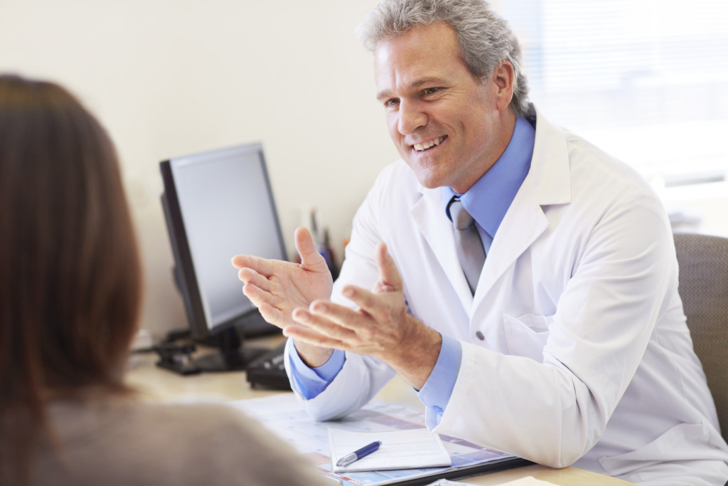 Mature doctor sitting at his desk and consulting with a patient